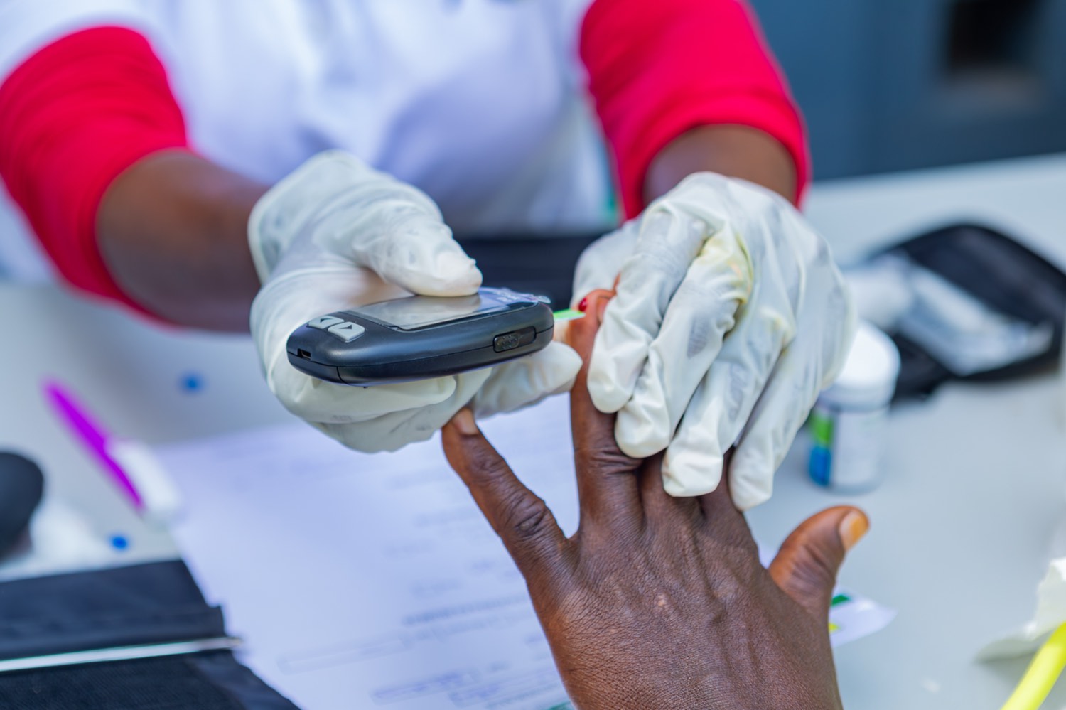 Un membre de l'équipe médicale réalise un test de glycémie sur le doigt d'un participant lors d'une journée de dépistage