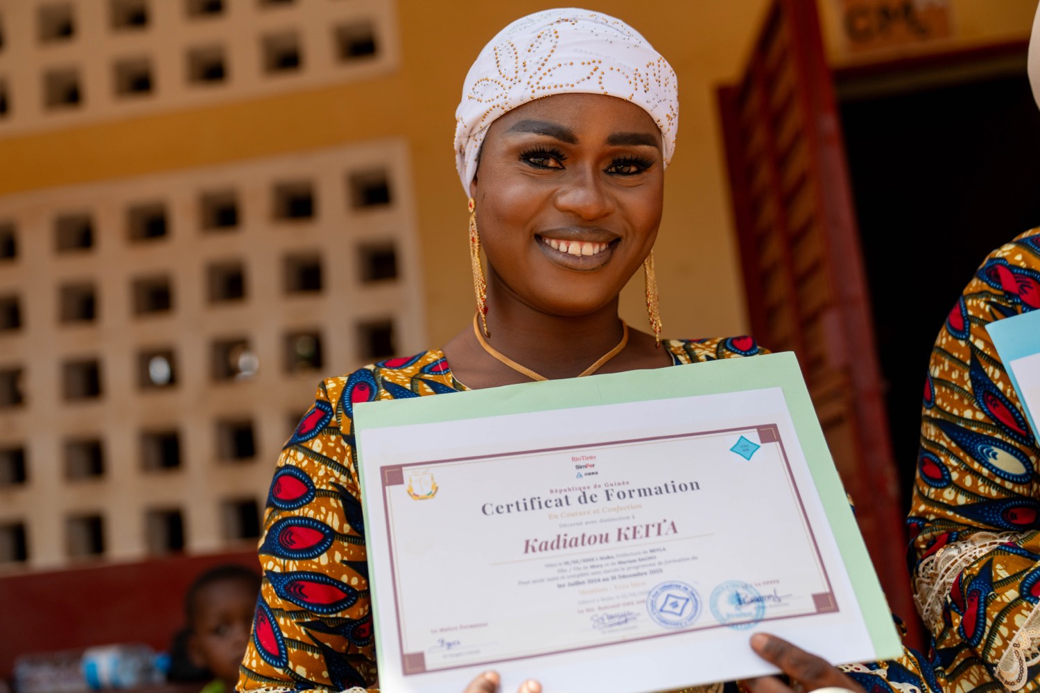 Kadiatou Keita, présidente de la coopérative, sourit en présentant son certificat de formation