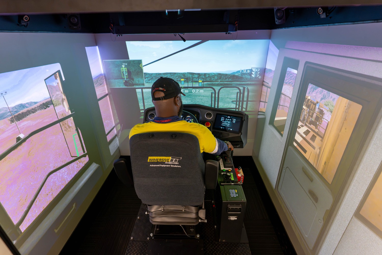 Un opérateur de SimFer installé dans un simulateur immersif entouré d’écrans de projection panoramiques
